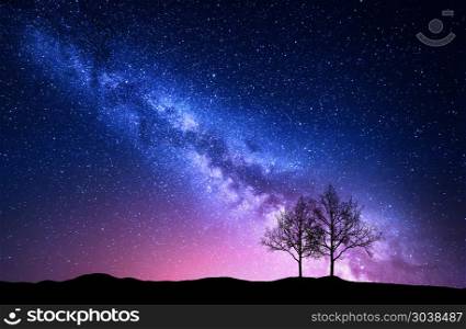 Starry sky with pink Milky Way and trees. Night landscape. Starry sky with pink Milky Way. Night landscape with alone trees on the hill against colorful milky way. Amazing galaxy. Nature background with beautiful universe. Astrophotography