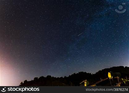 Stars and falling star over the forest and a house at the Troodos mountains in Kakopetria village in Cyprus