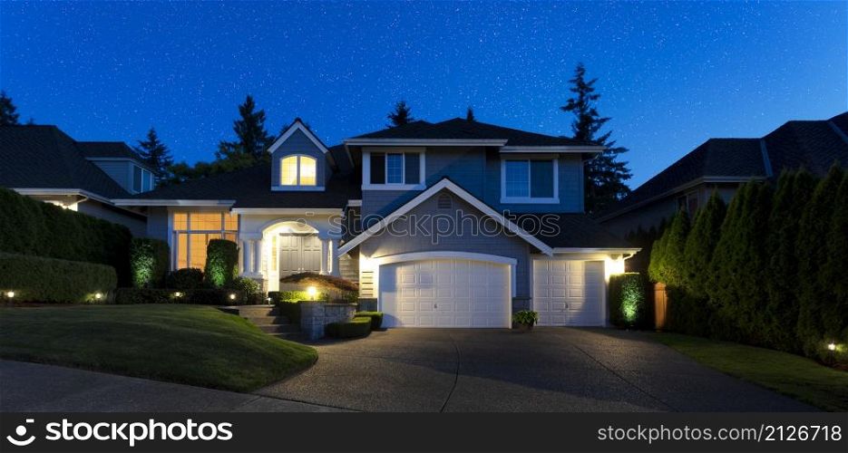 Stars coming out in late evening with front view of modern suburban home and yard
