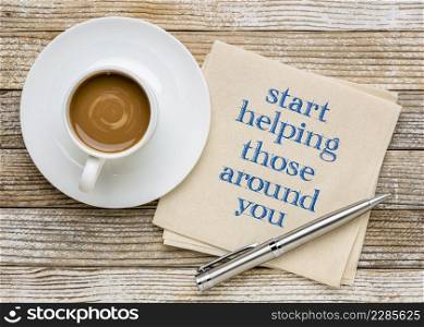 start helping those around you - inspirational advice or reminder, handwriting on a napkin with coffee, generosity and kindness concept