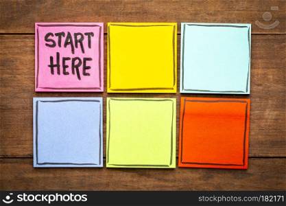 start here concept - handwriting on colorful sticky notes against rustic wood