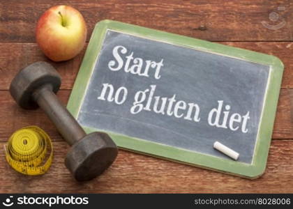 start no gluten diet advice - slate blackboard sign against weathered red painted barn wood with a dumbbell, apple and tape measure