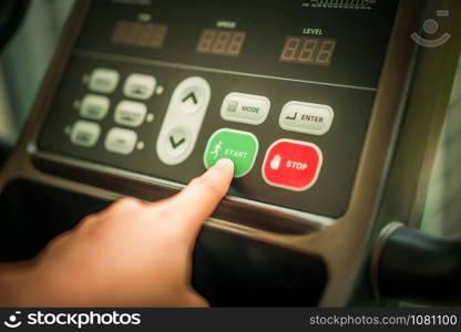 Start running - Hand pressing start button on treadmill control panel. Healthy lifestyle concept.