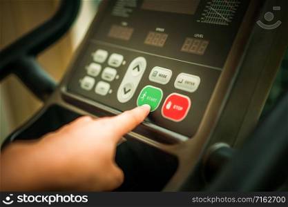Start running - Hand pressing start button on treadmill control panel. Healthy lifestyle concept.