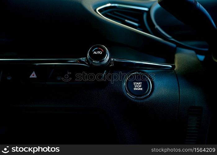 Start stop engine button of luxury car. Push up button for start or stop car engine in keyless automobile. Turn key with ignition system concept. Black ignition switch. Car air conditioning knob.