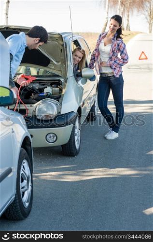 Starter cables man help to repair car two female friends