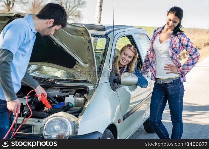 Starter cables man help to repair car two female friends