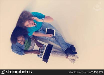 startup business and new mobile technology concept with young multiethnic couple in modern bright office interior working on laptop and tablet computer on new creative project and brainstorming top view