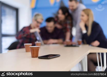 startup business team on meeting in modern bright office interior brainstorming, working on laptop and tablet computer. Smartphone on table in focus