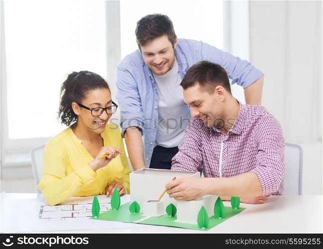 startup, education, architecture and office concept - smiling architects with house model and blueprint working in office