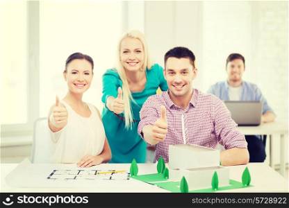 startup, education, architecture and office concept - smiling architects with house model and blueprint in office showing thumbs up