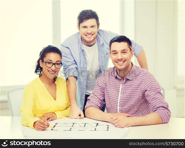 startup, education, architecture and office concept - three smiling architects with blueprint working in office