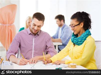 startup, education, fashion and office concept - smiling designers drawing sketches in office