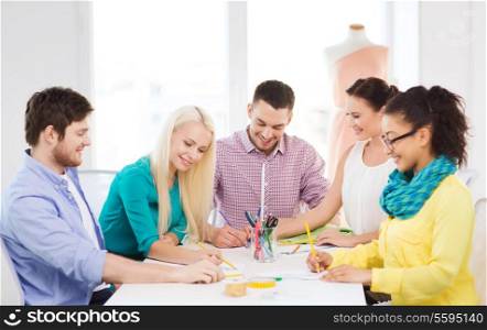 startup, education, fashion and office concept - smiling fashion designers working in office