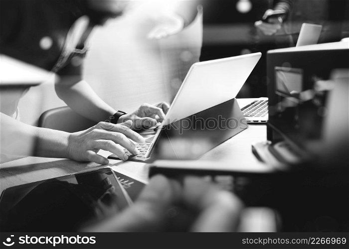 StartUp Programming Team. Website designer working digital tablet dock keyboard and computer laptop with smart phone and compact server on mable desk,black white        