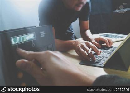 StartUp Programming Team. Website designer working digital tablet dock keyboard and computer laptop with smart phone and compact server on mable desk,light effect