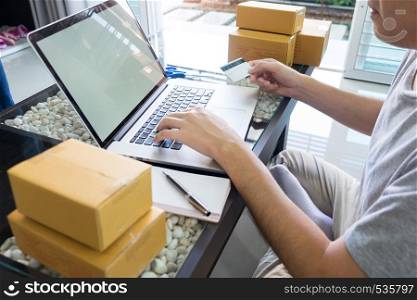 Startup small business SME, entrepreneur owner using smartphone or note book taking receive and checking online purchase shopping order to preparing pack product box