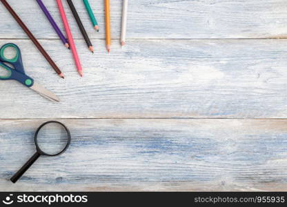 stationery and magnifier on light blue old wooden background. top view. flat lay