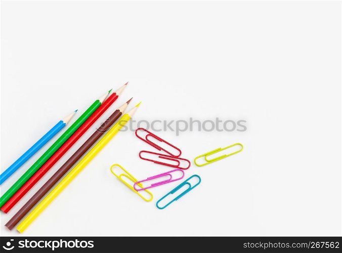 Stationery office supplies concept, Colored crayon pencils with colorful clips on white background with copy space. Top view.