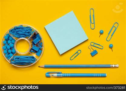 stationery paper clips, binders, buttons, pencil, pen and paper in blue on yellow background
