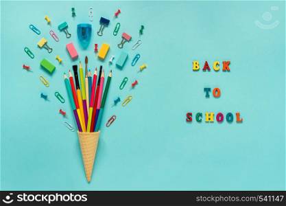 Stationery Pencils paintbrush paperclip in waffle ice cream cone. Text back to school Still life on blue background. Copy space Flat lay Top view Concept Education. Stationery Pencils paintbrush paperclip in waffle ice cream cone