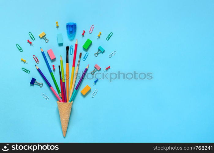 Stationery Pencils paintbrush paperclip in waffle ice cream cone. Still life on blue background. Copy space Flat lay Top view Concept Education . Stationery Pencils paintbrush paperclip in waffle ice cream cone