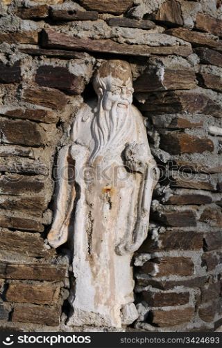 Statue of an old man in the niche in the brick wall