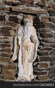 Statue of an old man in the niche in the brick wall