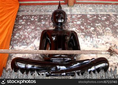 Statue of black Buddha in corridor of wat Suthat, Bangkok, Thailand