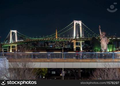 Statue of Liberty and Rainbow bridge at night time, located at Odaiba Tokyo, Japan