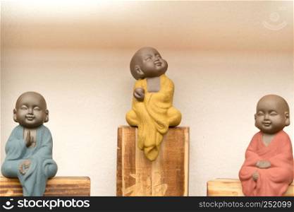statue of little monk with colorful dress sitting on the wooden box