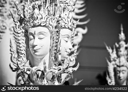 Statue of mythological head in Wat Rong Khun. Wat Rong Khun is a contemporary unconventional Buddhist temple in Chiang Rai, Chiangmai province, Thailand. It is designed in white color.