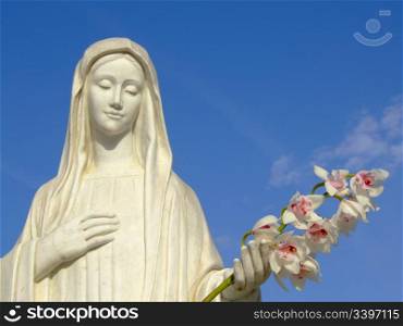 statue of saint Marion of Medjugorje holding flowers on beautiful day