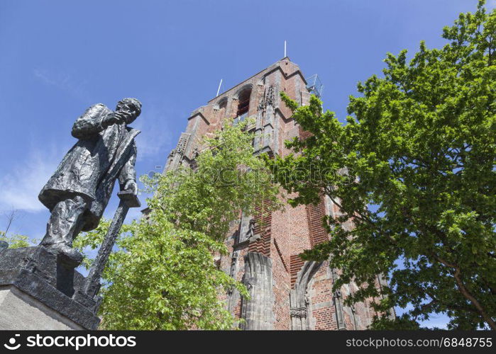 statue of troelstra next to oldehove tower in the centre of leeuwarden, capital of friesland, in the netherlands with blue sky