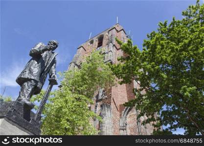 statue of troelstra next to oldehove tower in the centre of leeuwarden, capital of friesland, in the netherlands with blue sky