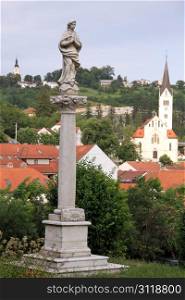 Statue of Virgin Mary on the column and old church in town Krapina, Croatia