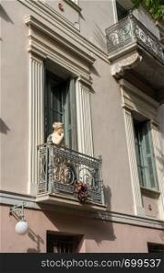 Statue on a wrought iron balcony in ancient district or neighborhood of Plaka in Athens by the Acropolis. Statue on balcony of ancient residential district of Plaka in Athens Greece