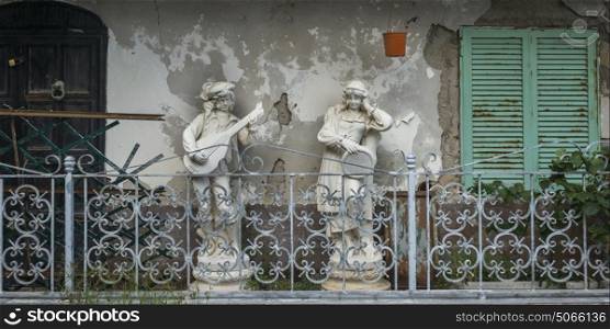 Statues by railings on weathered building, Ischia Island, Campania, Italy