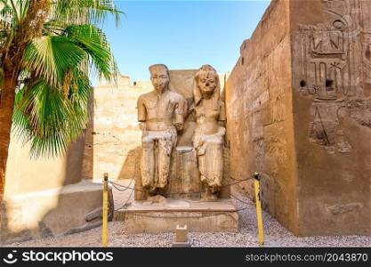 Statues of sitting pharaoh and his wife in Luxor Temple, Egypt. Statues of pharaohs