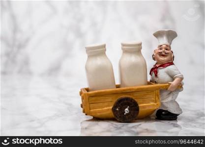 Statuette of a cook with shakers on white marble background