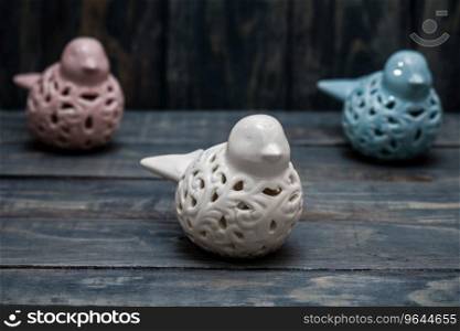 Statuettes of white, blue and pink birds on blue wooden background