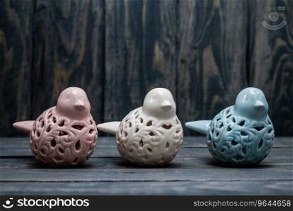 Statuettes of white, blue and pink birds on blue wooden background