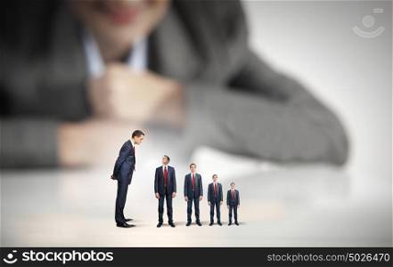 Status in business. Businesswoman looking at miniature of business people of different sizes