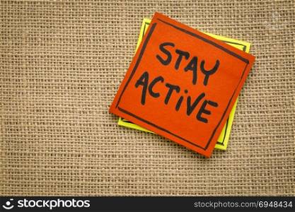 Stay active - handwriting on a sticky note against burlap canvas
