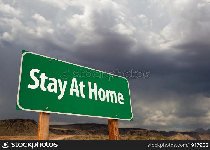 Stay At Home Green Road Sign Against An Ominous Cloudy Sky.