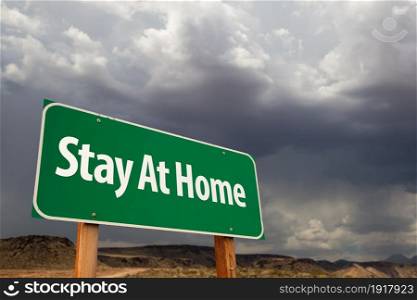 Stay At Home Green Road Sign Against An Ominous Cloudy Sky.
