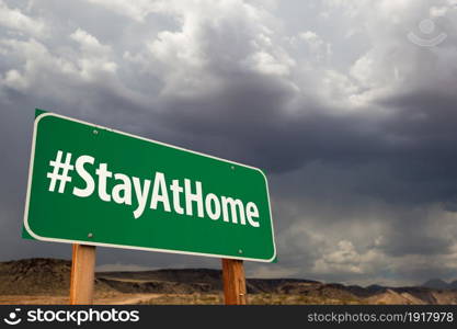 #Stay At Home Green Road Sign Against An Ominous Cloudy Sky.