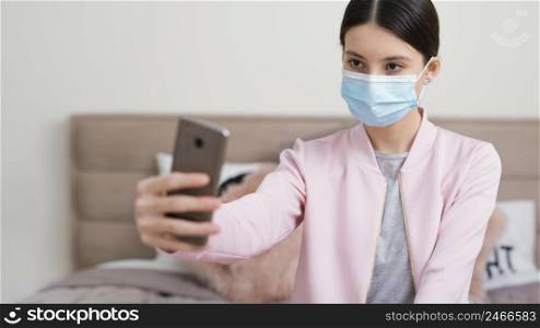 stay indoors woman with medical mask taking selfies