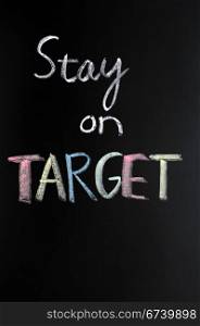 Stay on target written in chalk on blackboard
