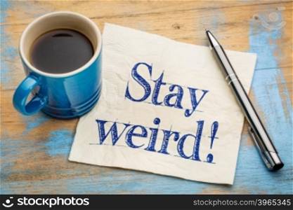 Stay weird advice - handwriting on a napkin with a cup of espresso coffee
